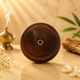 Leela dark wooden circular incense burner featuring a central brass holder and four surrounding incense-stick holes.