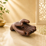 Leela dark brown clay incense burner shaped like two offering hands with an incense hole in the palm.