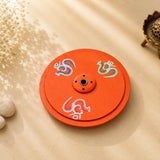 Leela round orange wooden incense burner hand-painted with colourful Om symbols and a central incense holder.