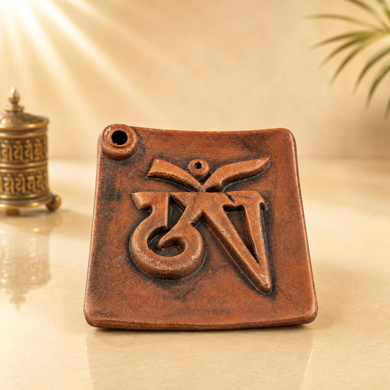 Leela terracotta incense burner featuring a raised Tibetan Om symbol and two incense-stick holes on a square tray.
