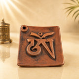 Leela terracotta incense burner featuring a raised Tibetan Om symbol and two incense-stick holes on a square tray.